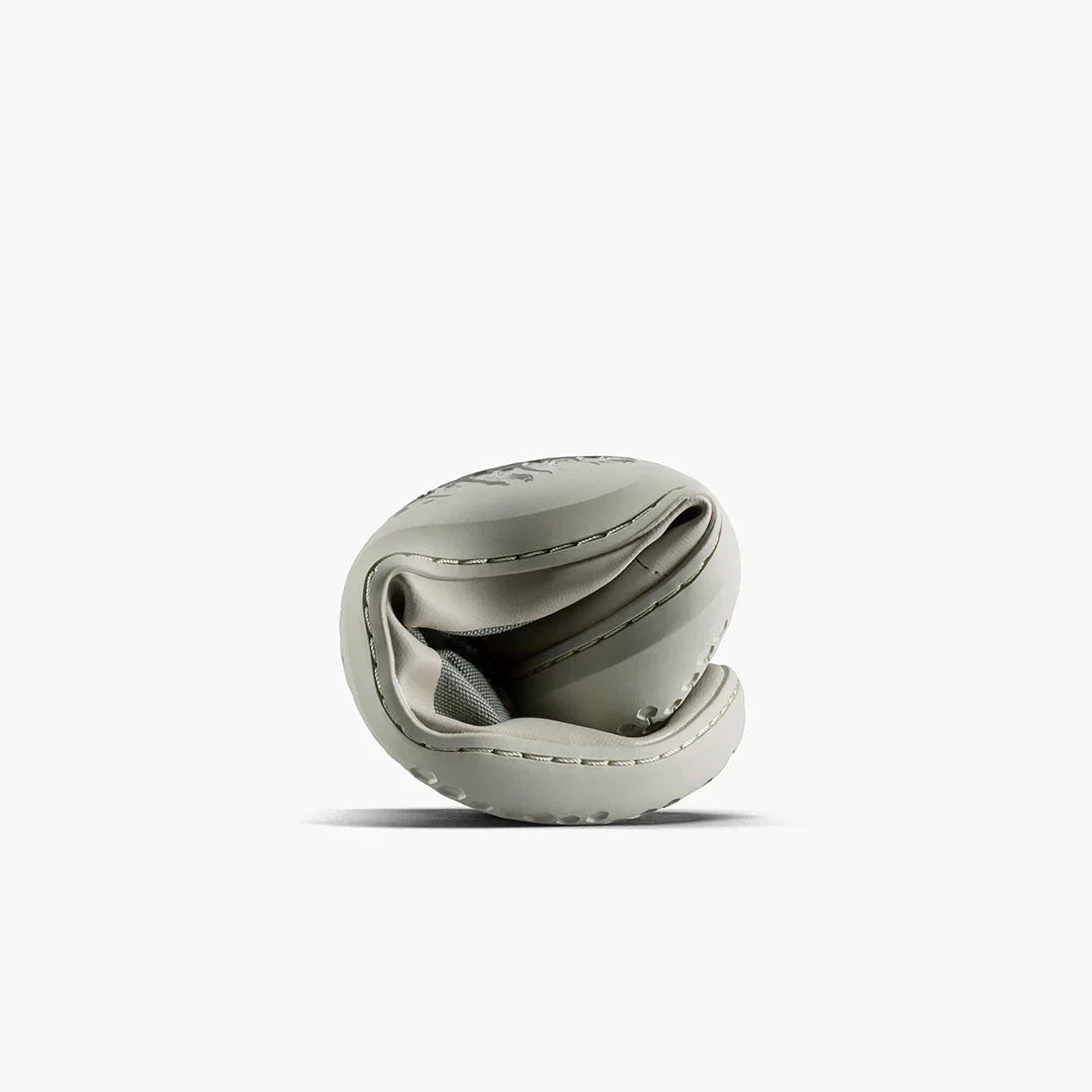 Flexible light gray sneaker folded to show softness and bendability on white background