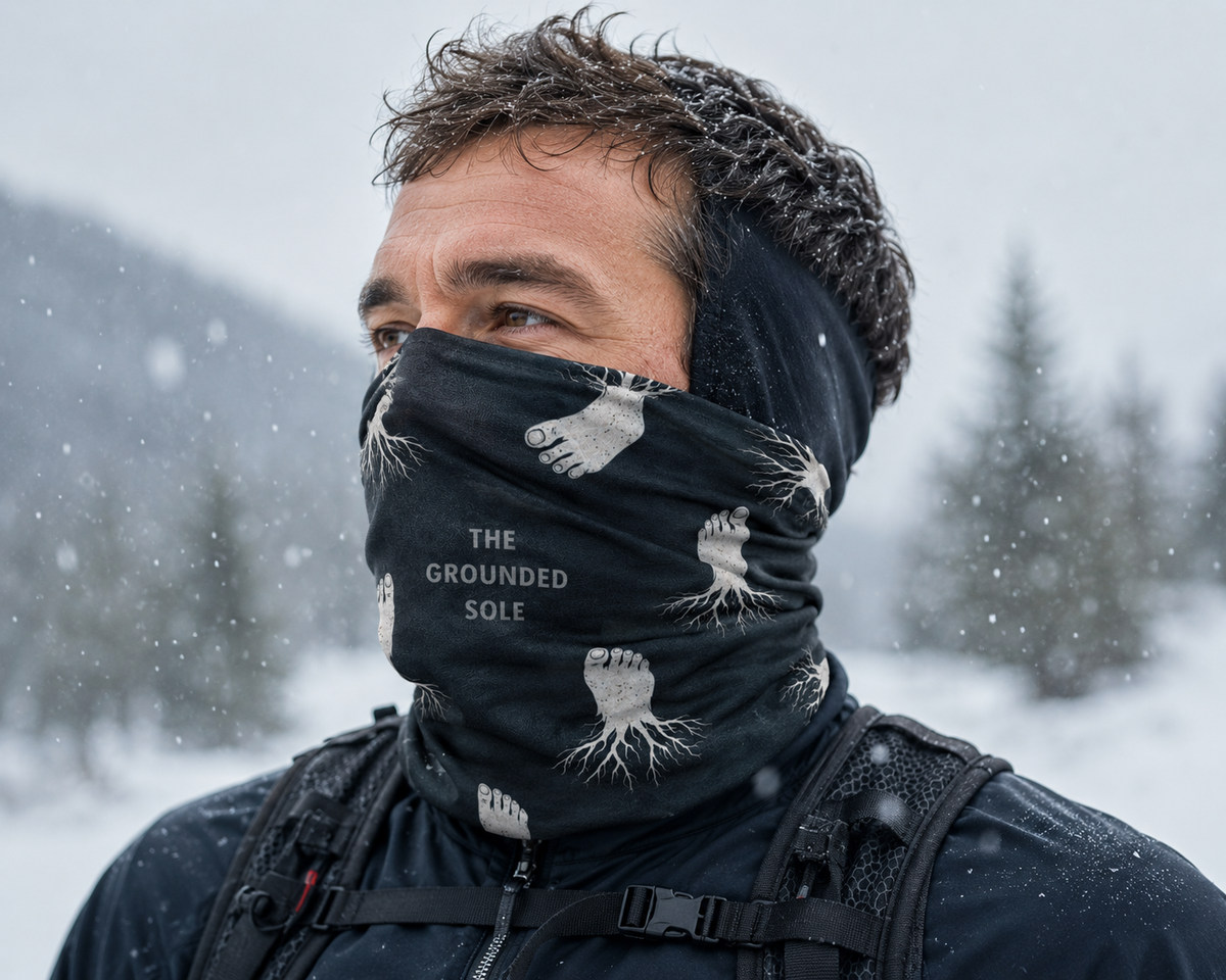 Person wearing a black neck gaiter with brand logo in a snowy landscape