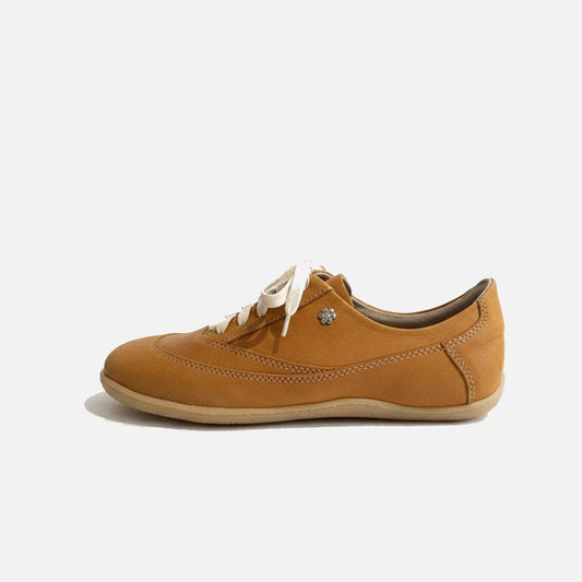 Brown sneaker with white laces on a light beige background