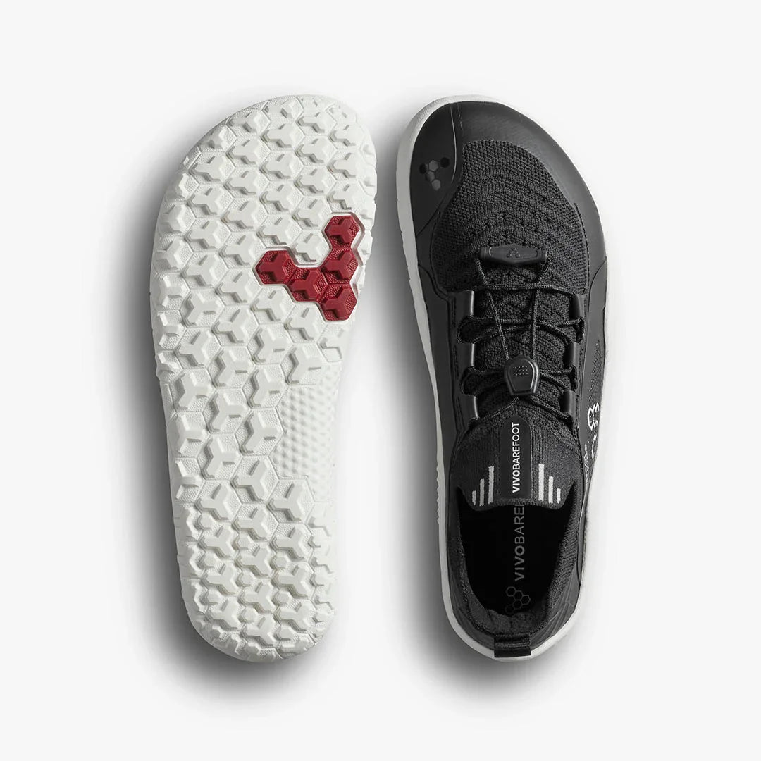 Black Vivobarefoot minimalist shoe with white textured sole featuring red hexagon detail