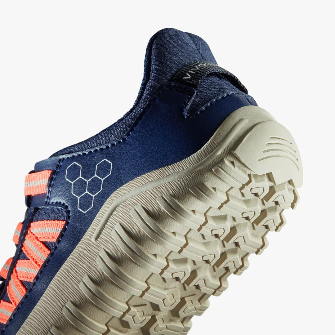 Close-up of navy and coral trail running shoe with textured beige sole and hexagonal logo