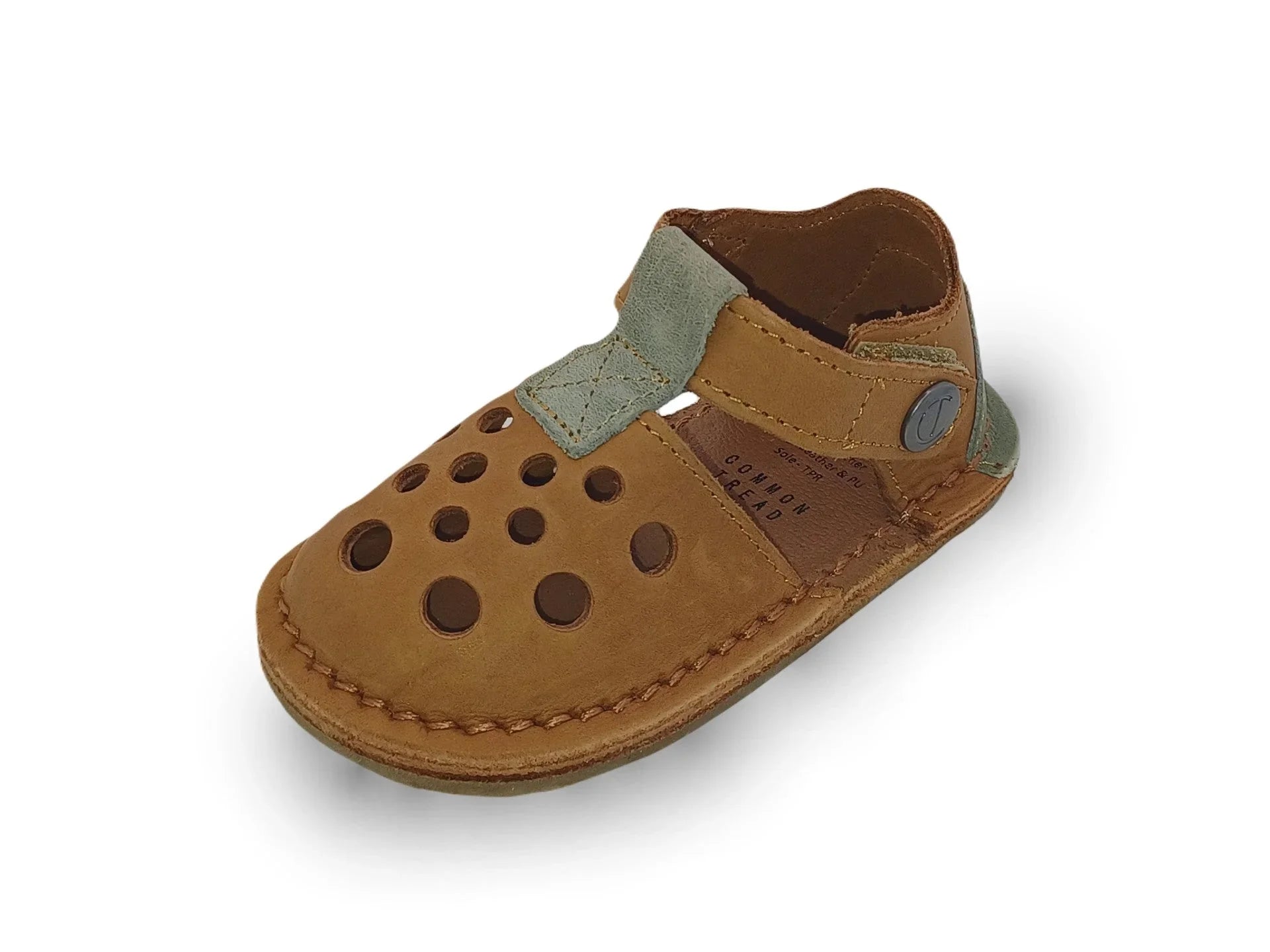 Brown baby leather sandal with circular cutouts and green strap detail on white background
