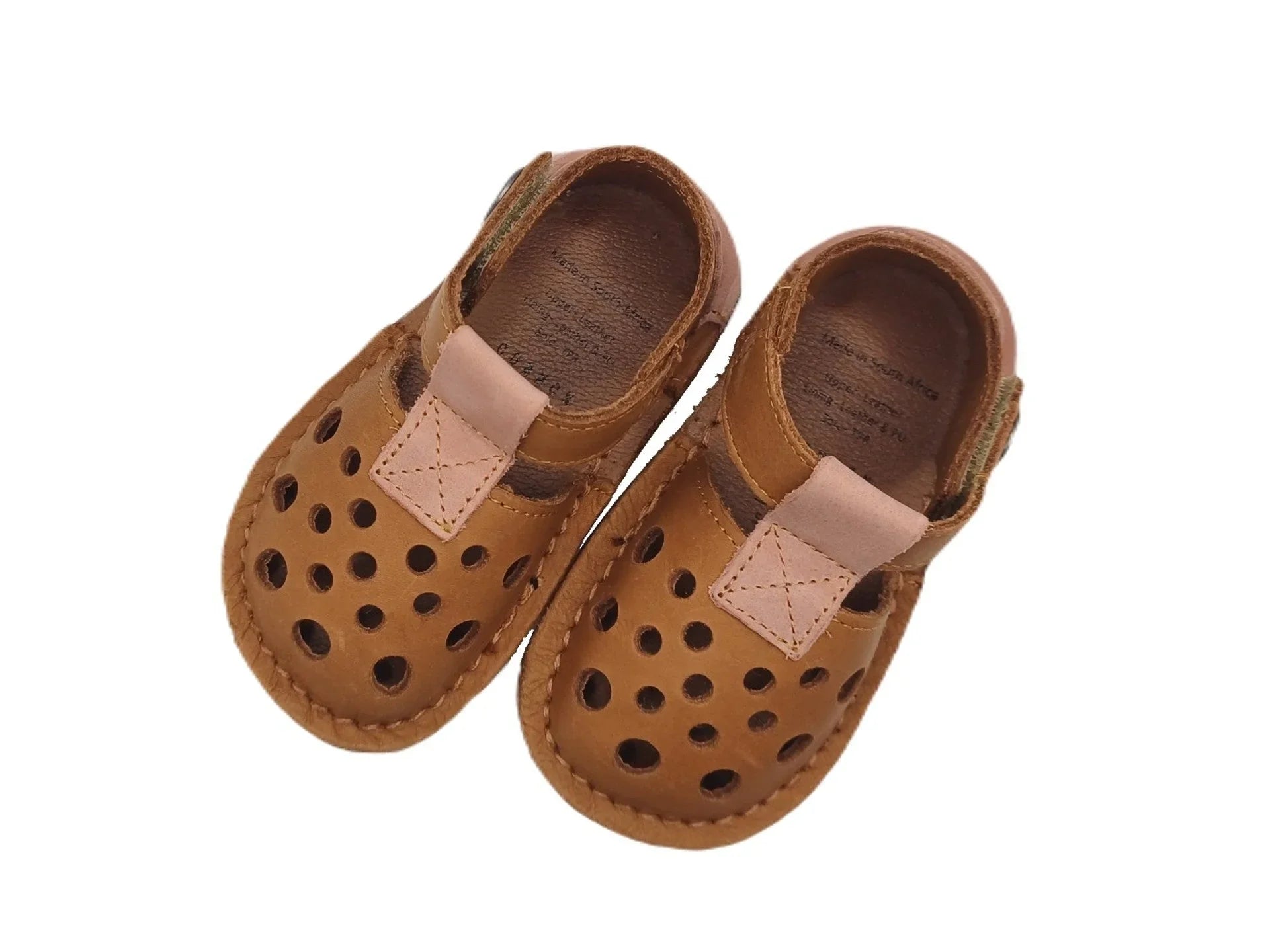 Brown leather baby shoes with perforated holes and velcro straps on white background