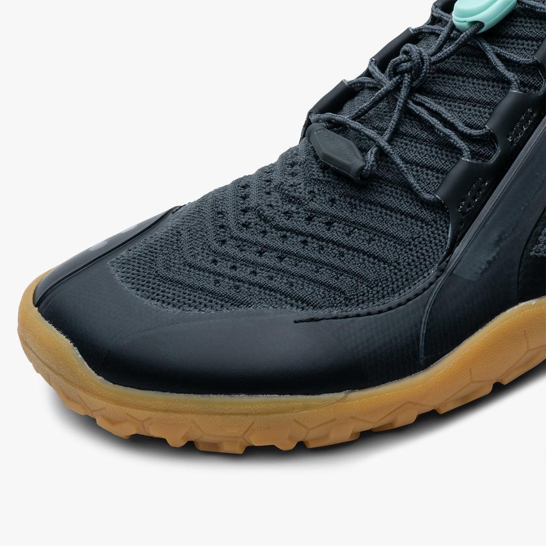 Close-up of black knit athletic shoe with gum rubber sole and lace detail