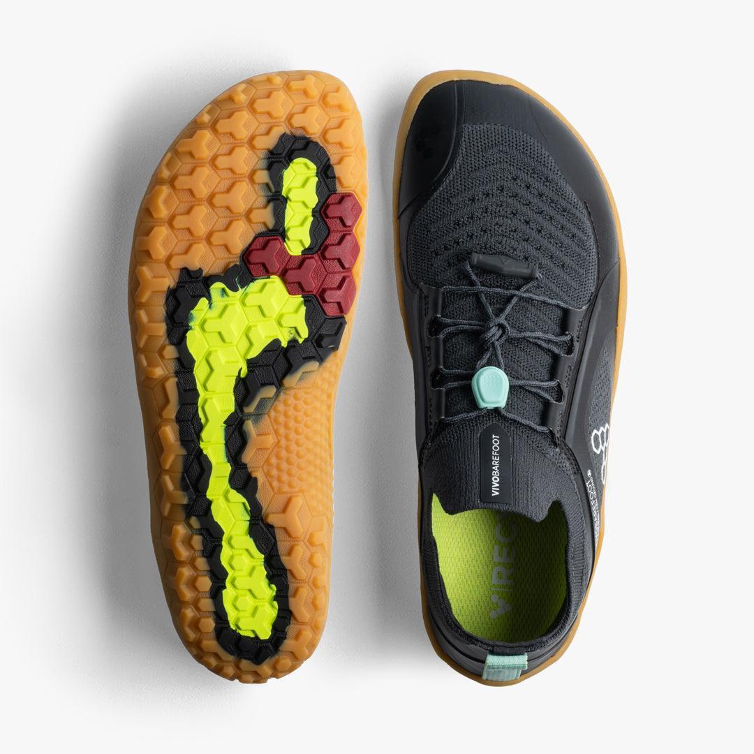 Black Vivobarefoot barefoot shoe with hexagonal patterned gum sole featuring red and yellow accents