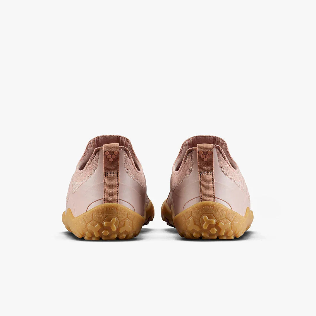 Back view of pink minimalist barefoot shoes with textured brown rubber soles on white background