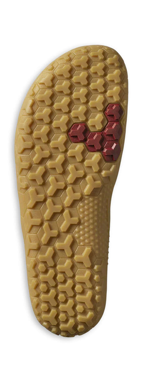 Close-up of beige shoe outsole with hexagonal and T-shaped tread pattern and red hexagonal detail