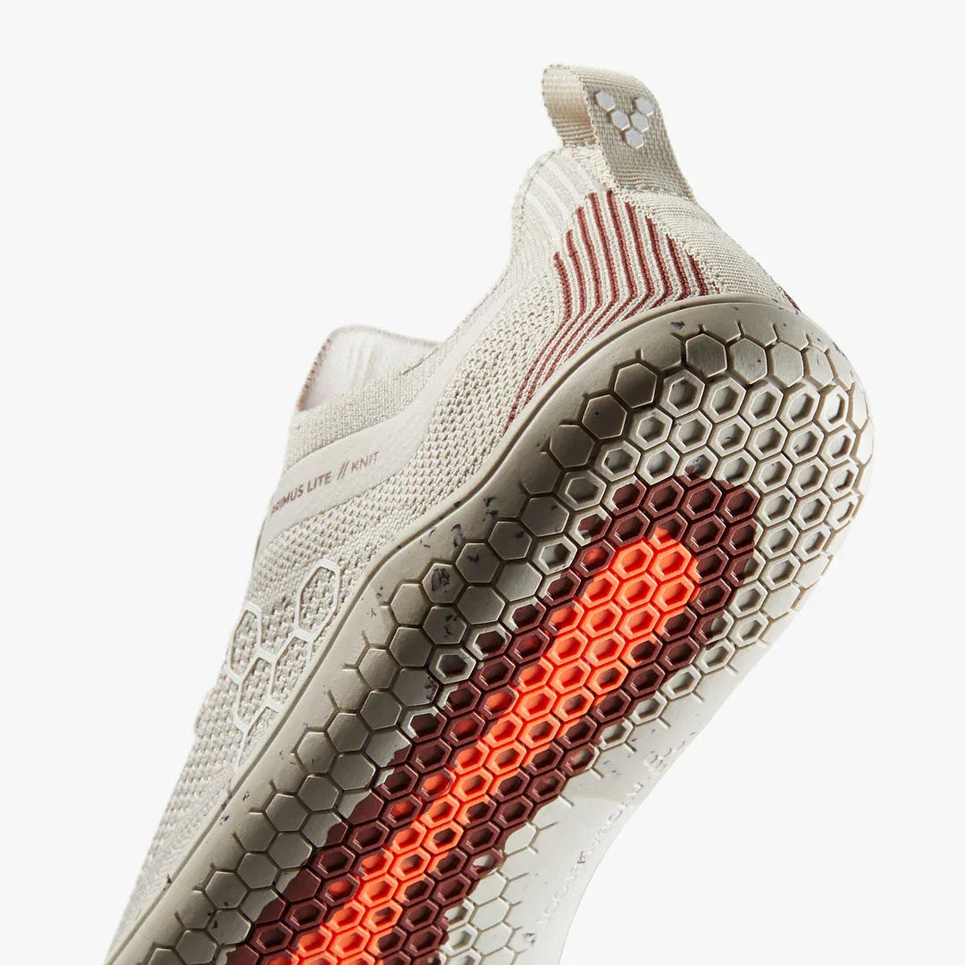 Close-up of beige knit athletic shoe sole with hexagonal pattern and orange tread detail