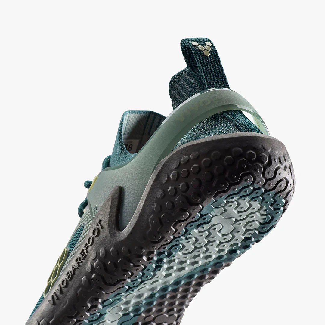 Closeup of teal and black Vivobarefoot athletic shoe sole with textured grip pattern and pull tab