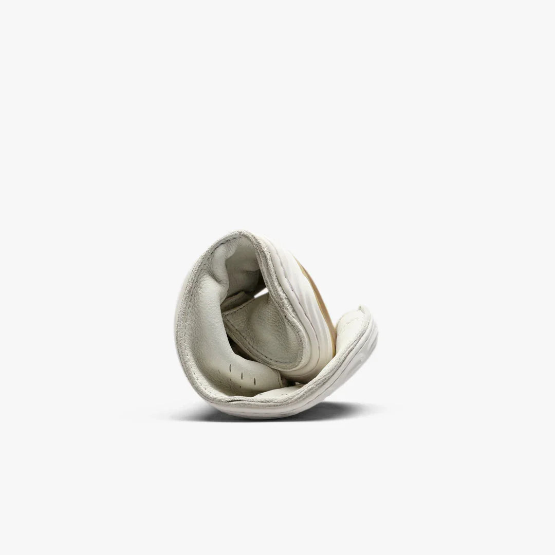 White flexible leather shoe rolled up on plain white background