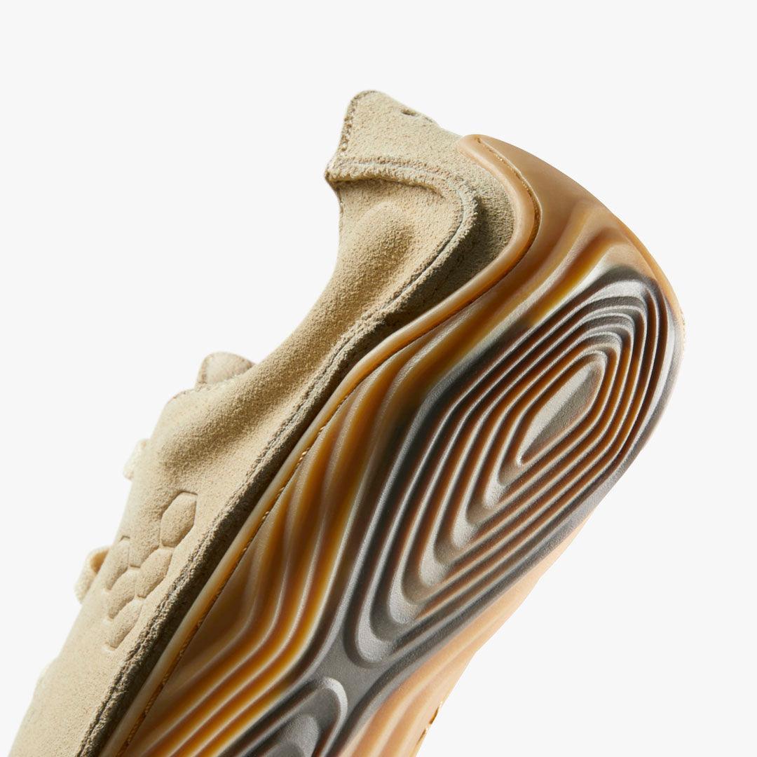 Close-up of beige suede sneaker with textured honeycomb design and wavy gum rubber sole