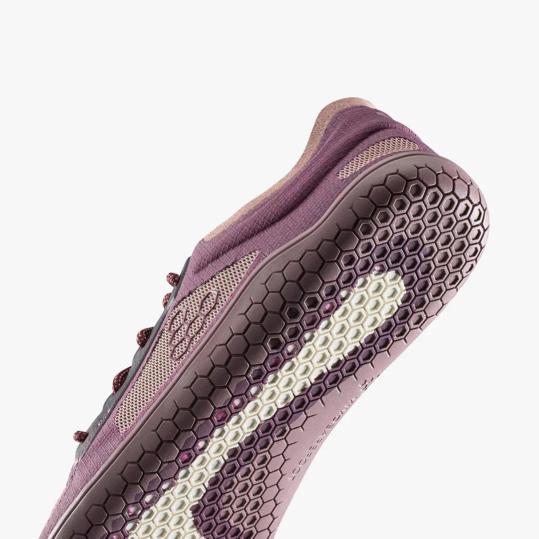 Close-up of purple athletic shoe sole with hexagonal tread pattern and breathable fabric upper