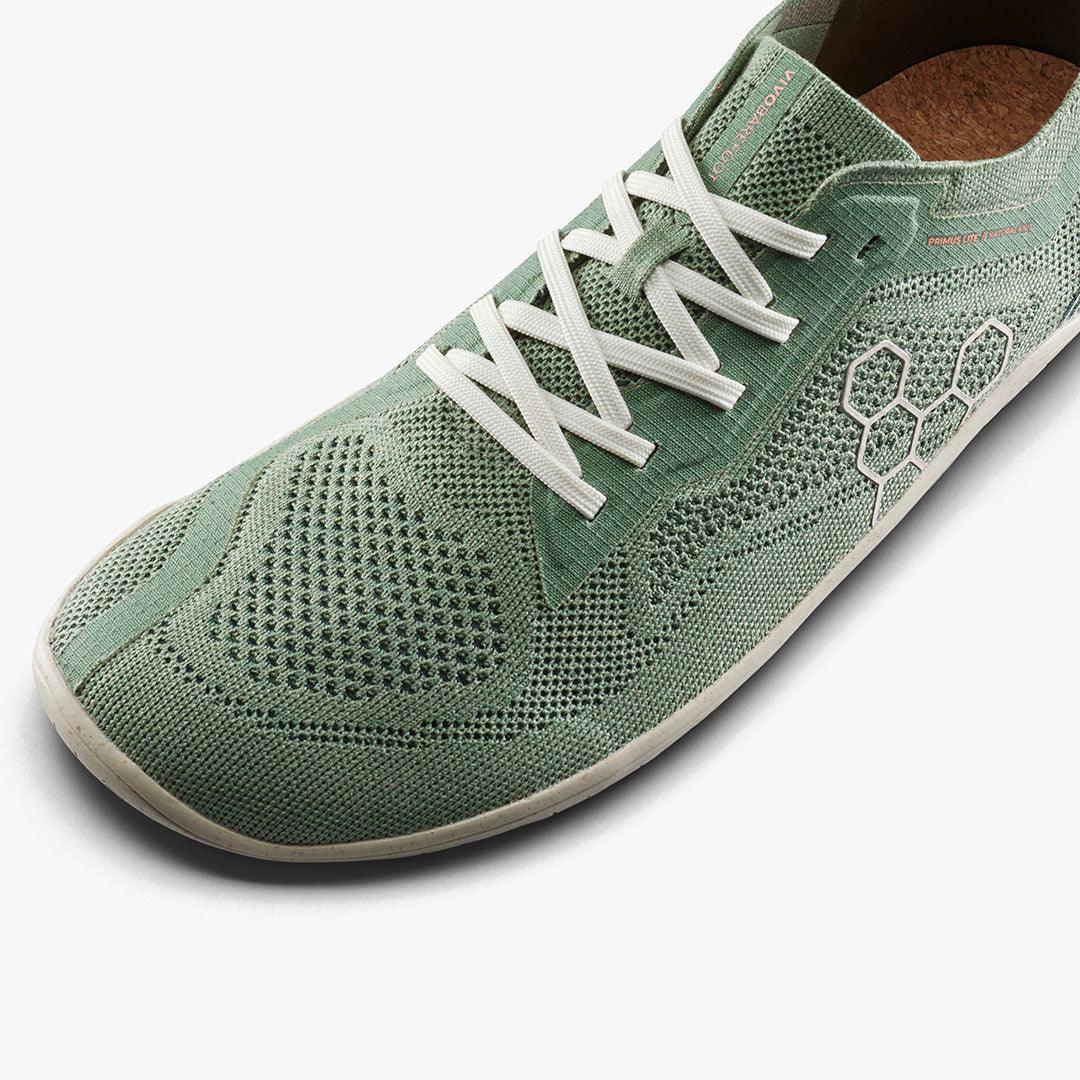 Close-up of light green breathable knit sneaker with white laces and hexagonal pattern