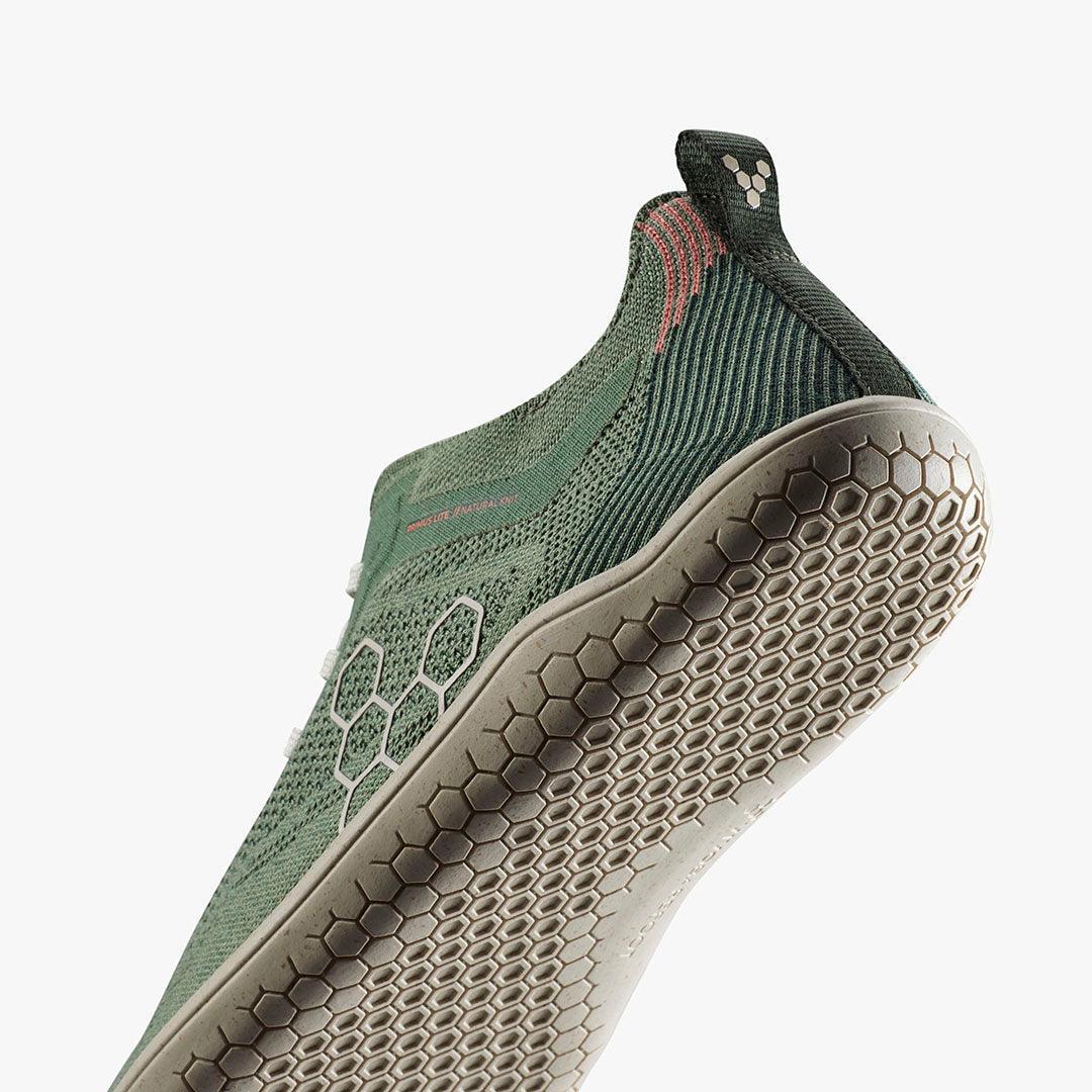 Closeup of green knit slip-on athletic shoe with hexagonal patterned sole and pull tab
