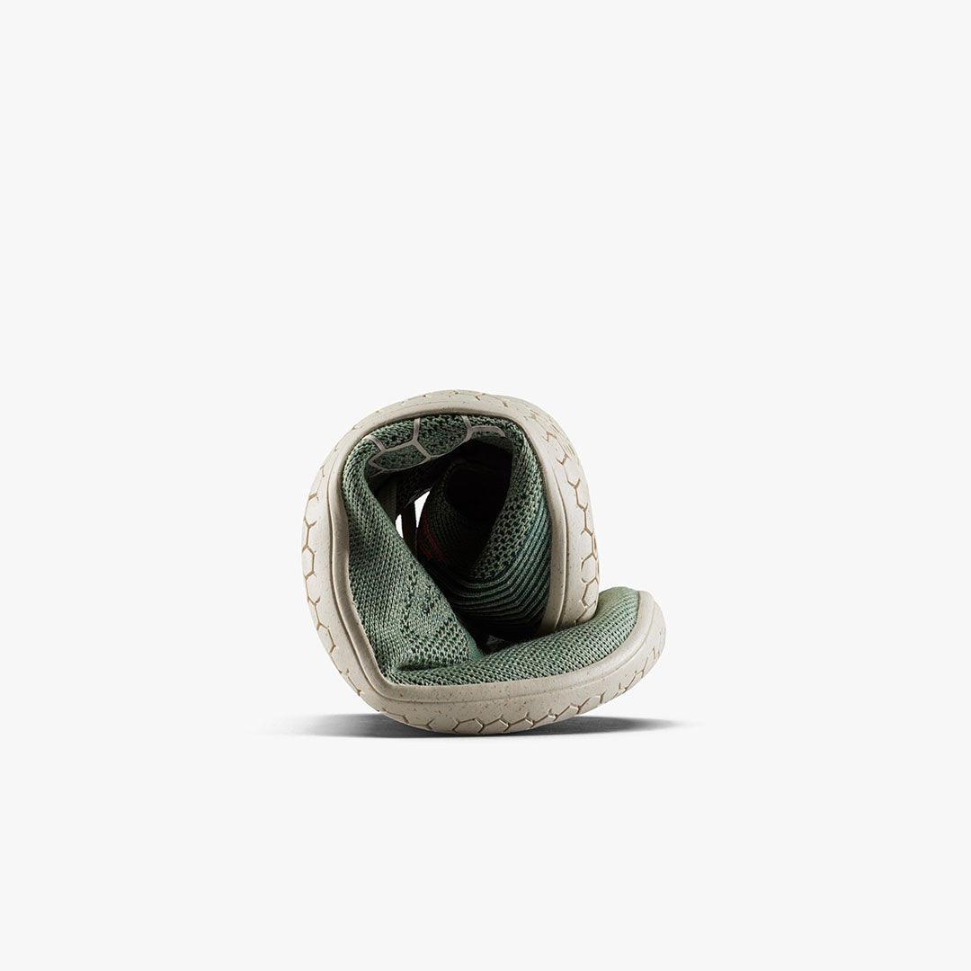 Rolled flexible green knit sneaker with beige grip sole isolated on white background