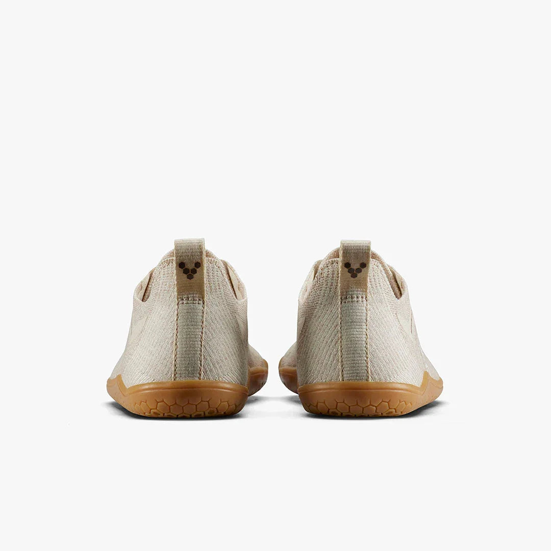 Back view of beige minimalist sneakers with tan rubber soles on white background