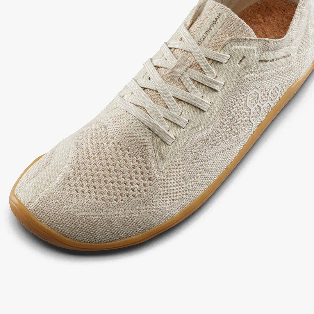 Close-up of a beige knit sneaker with natural cork insole and gum sole, featuring laces and breathable mesh design