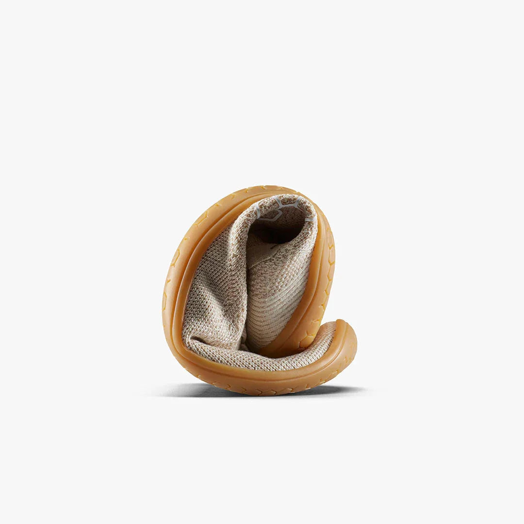 beige flexible shoe with textured sole rolled up on white background