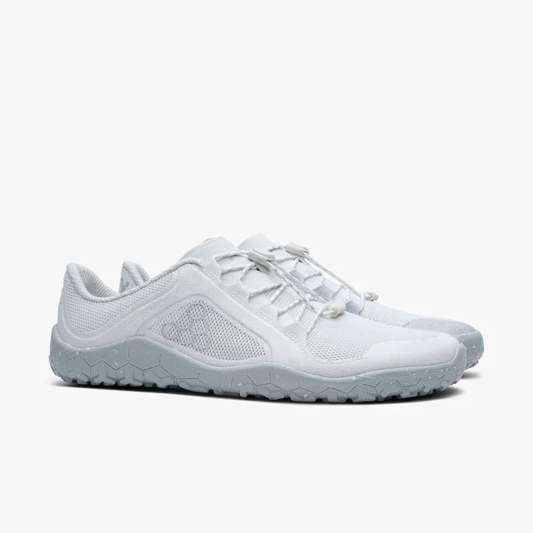 Pair of white minimalist athletic shoes with gray textured soles and hexagonal pattern on sides