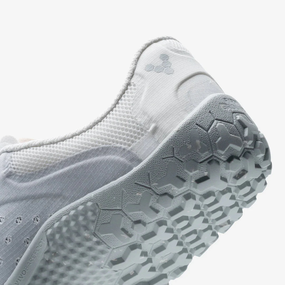 Close-up of white minimalist sneaker with textured hexagonal sole and mesh upper material