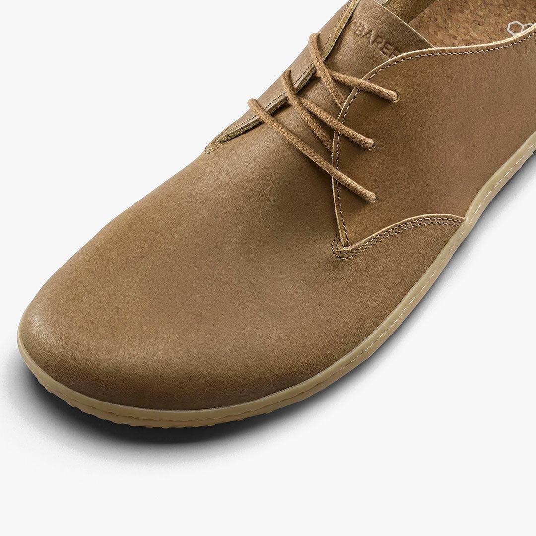 Close-up of a tan leather casual lace-up shoe with beige sole on white background
