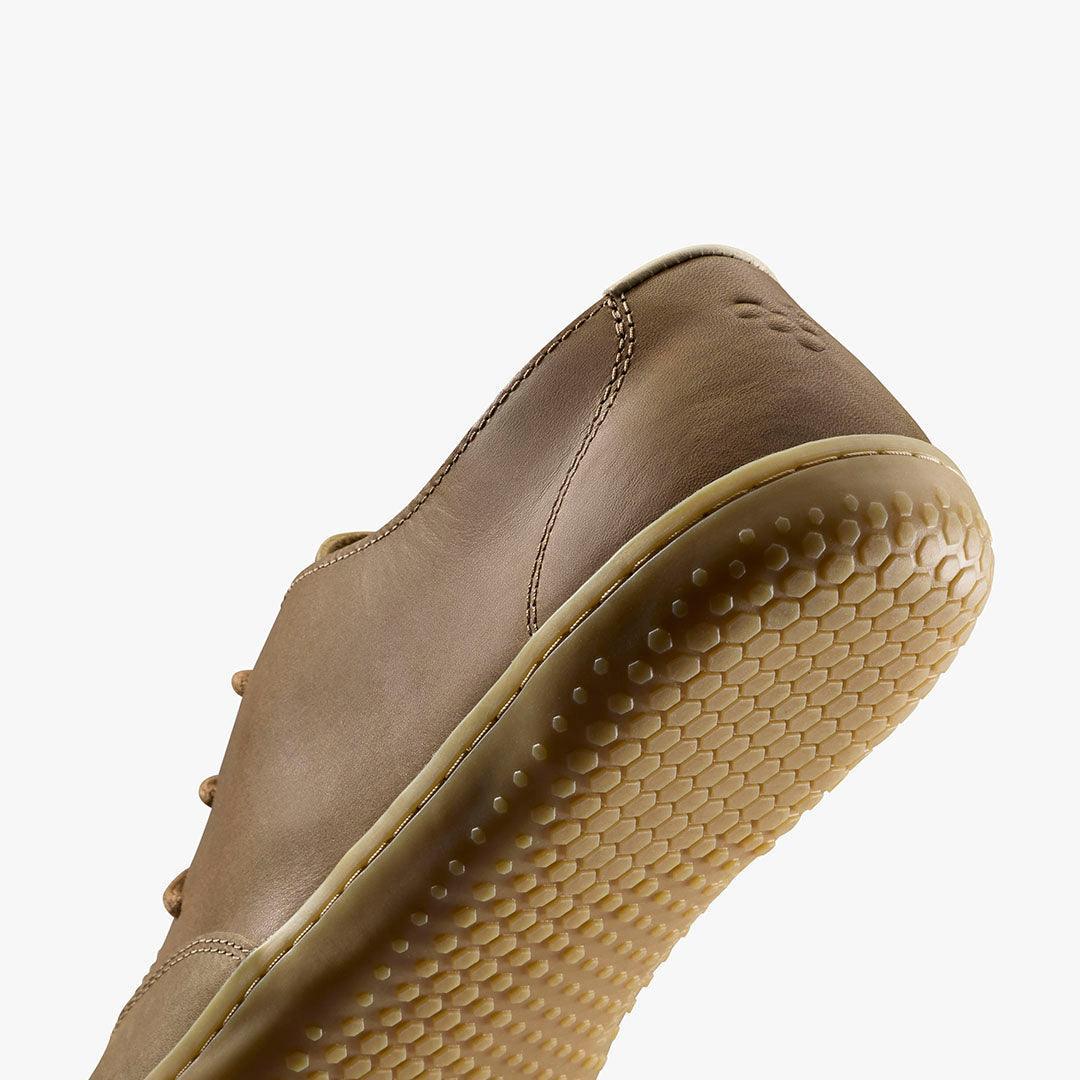 Close-up of brown leather sneaker sole with hexagonal tread pattern on white background