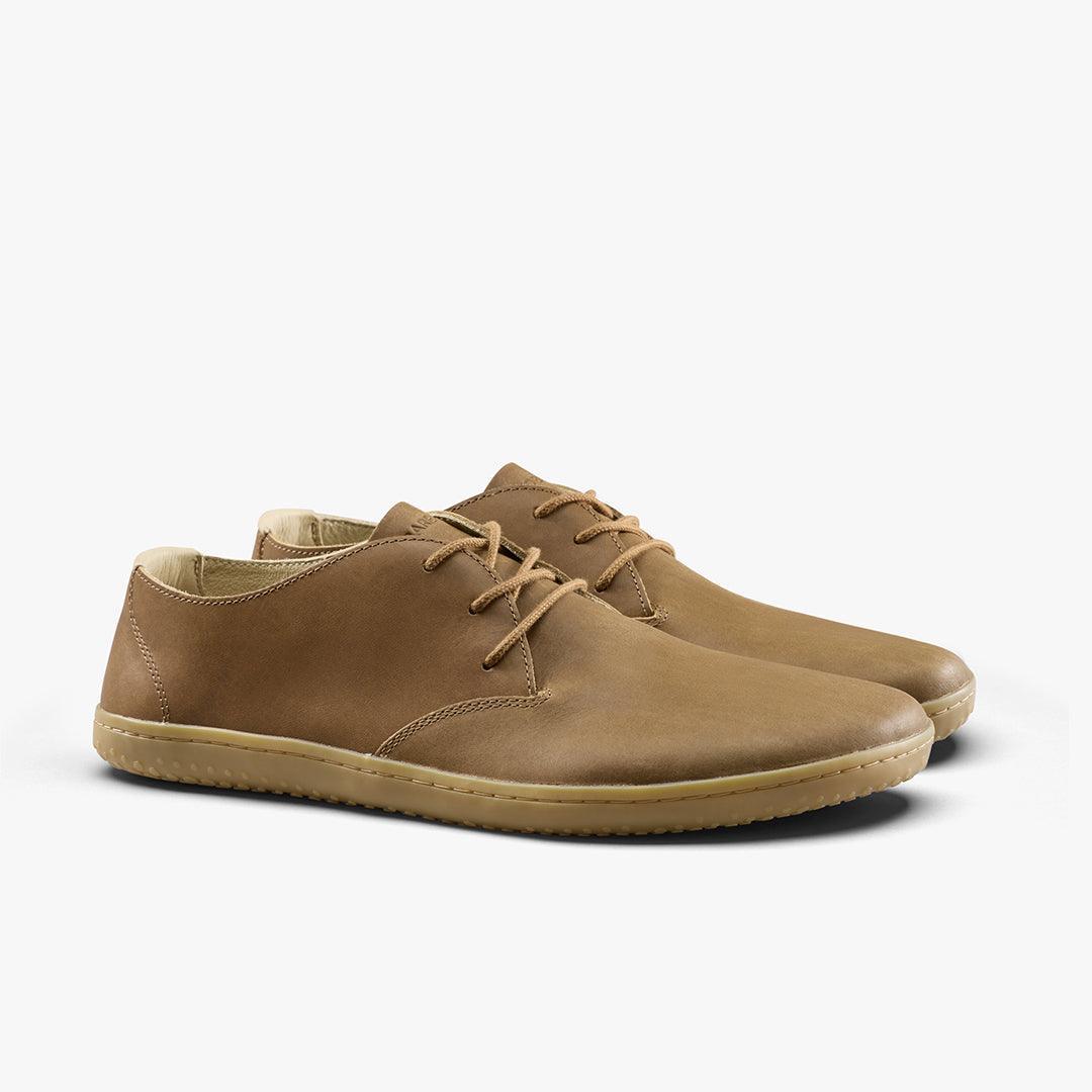 Pair of casual brown leather lace-up shoes with beige rubber soles on a white background