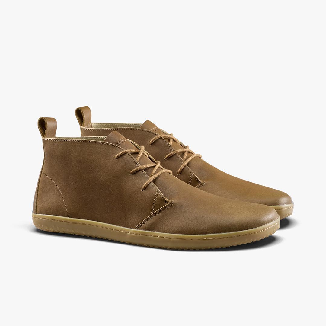 Pair of brown leather chukka boots with beige rubber soles and laces on white background