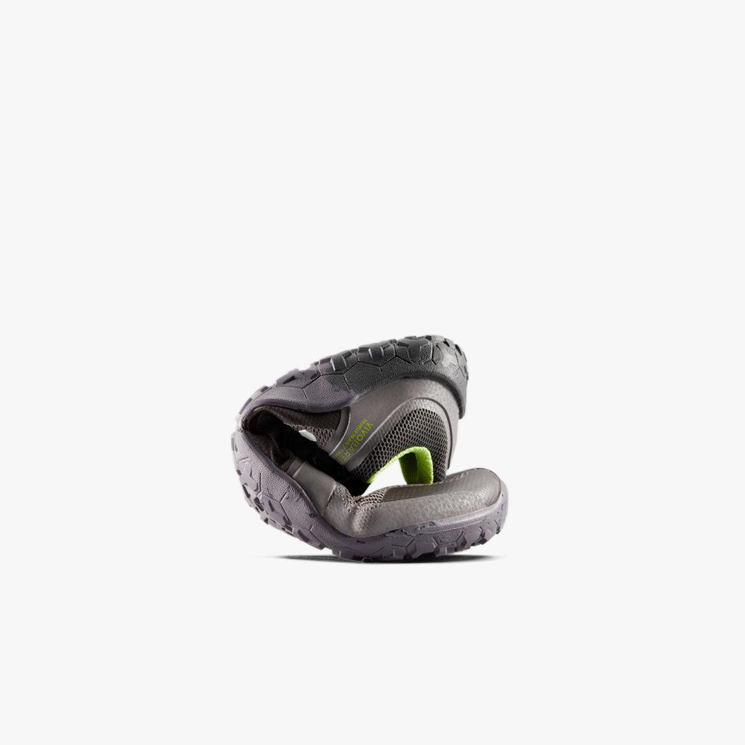 Flexible gray and green trail running shoe curled to demonstrate flexibility on white background