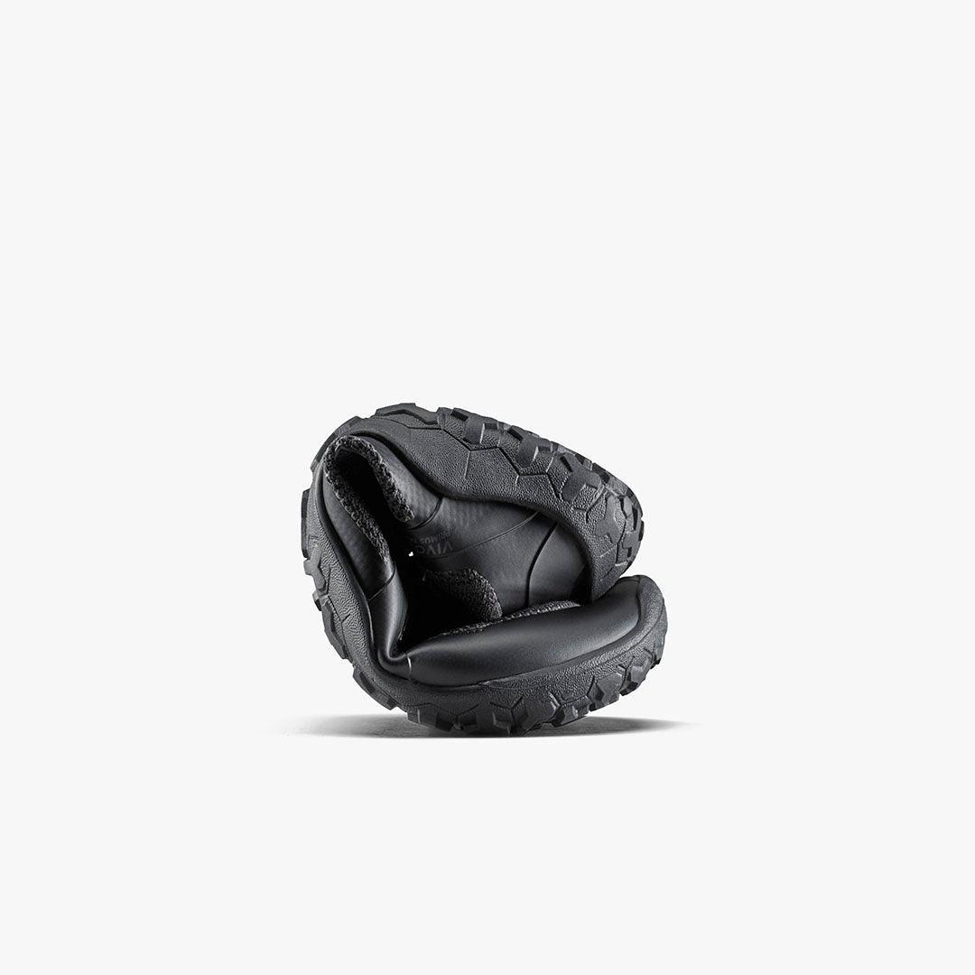 Black barefoot shoe curled to show flexible sole, sustainable footwear by The Grounded Sole