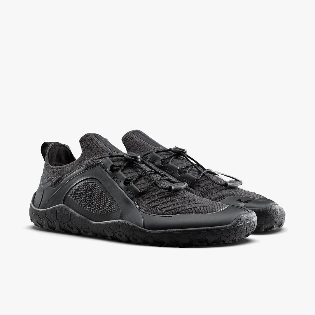 Black minimalist barefoot shoes with textured soles and mesh uppers on white background
