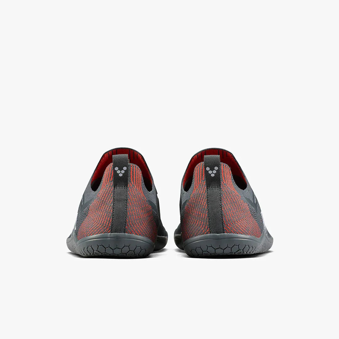 Back view of black and red minimalist barefoot running shoes with textured soles on white background