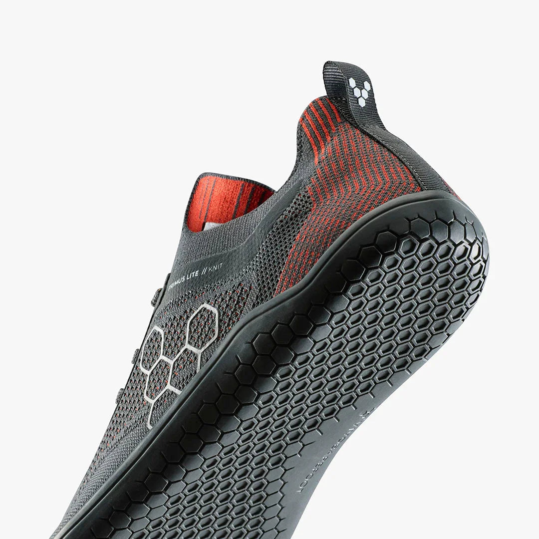 Close-up of black and red Vivobarefoot Primus Lite II Knit shoe with hexagonal sole pattern
