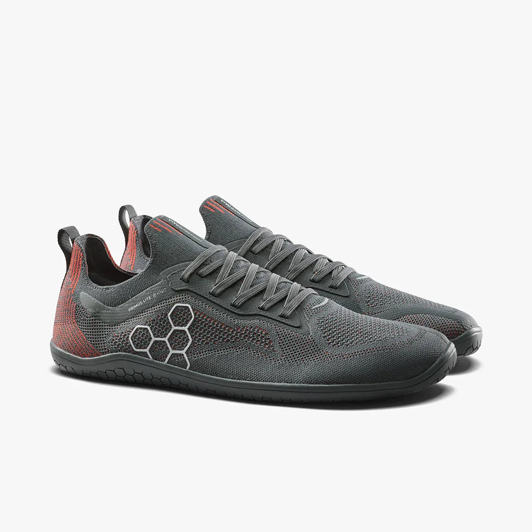 Gray and red lightweight athletic shoes with knitted upper and hexagon pattern on sole