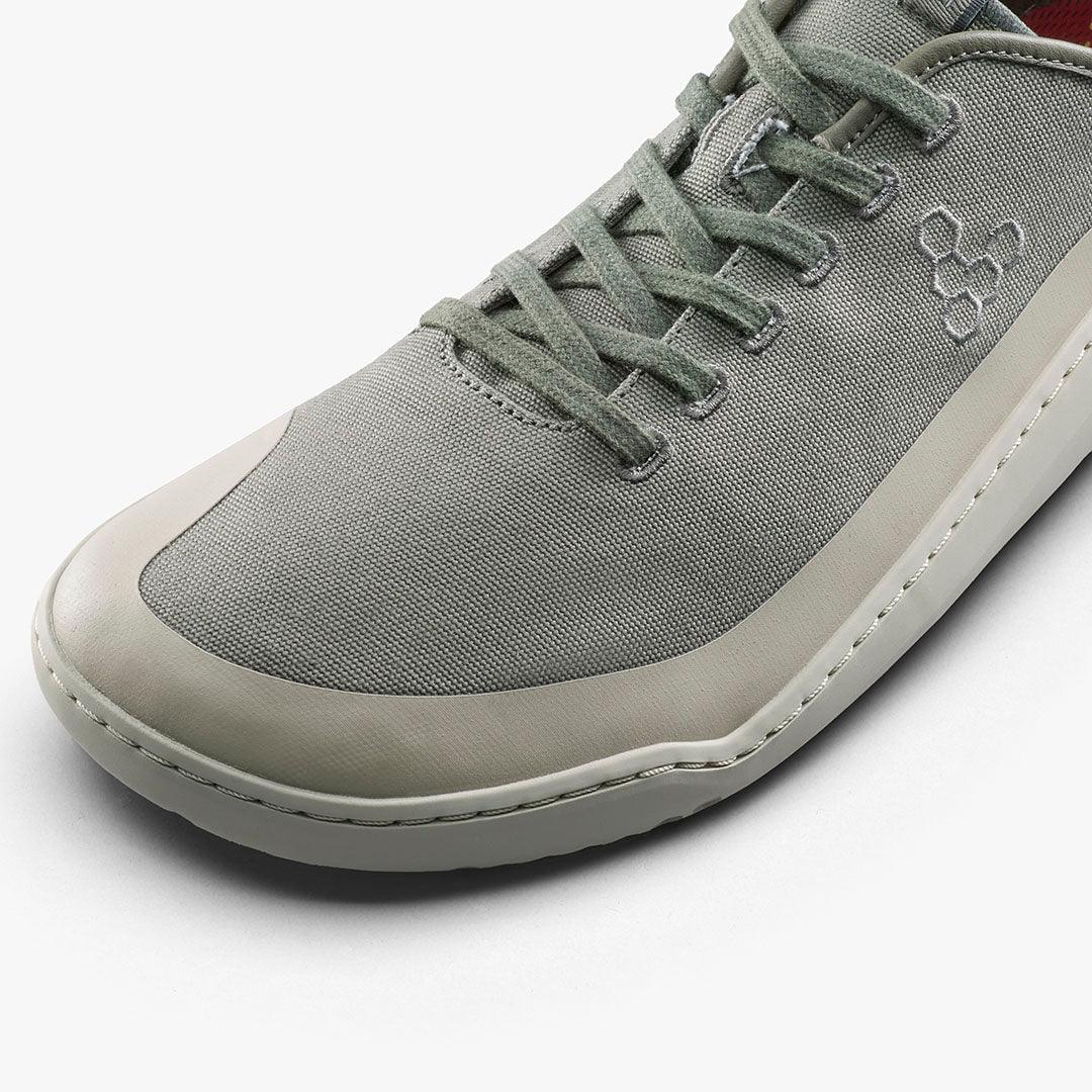 Close-up of modern gray sneaker with canvas upper, green laces, and rubber sole