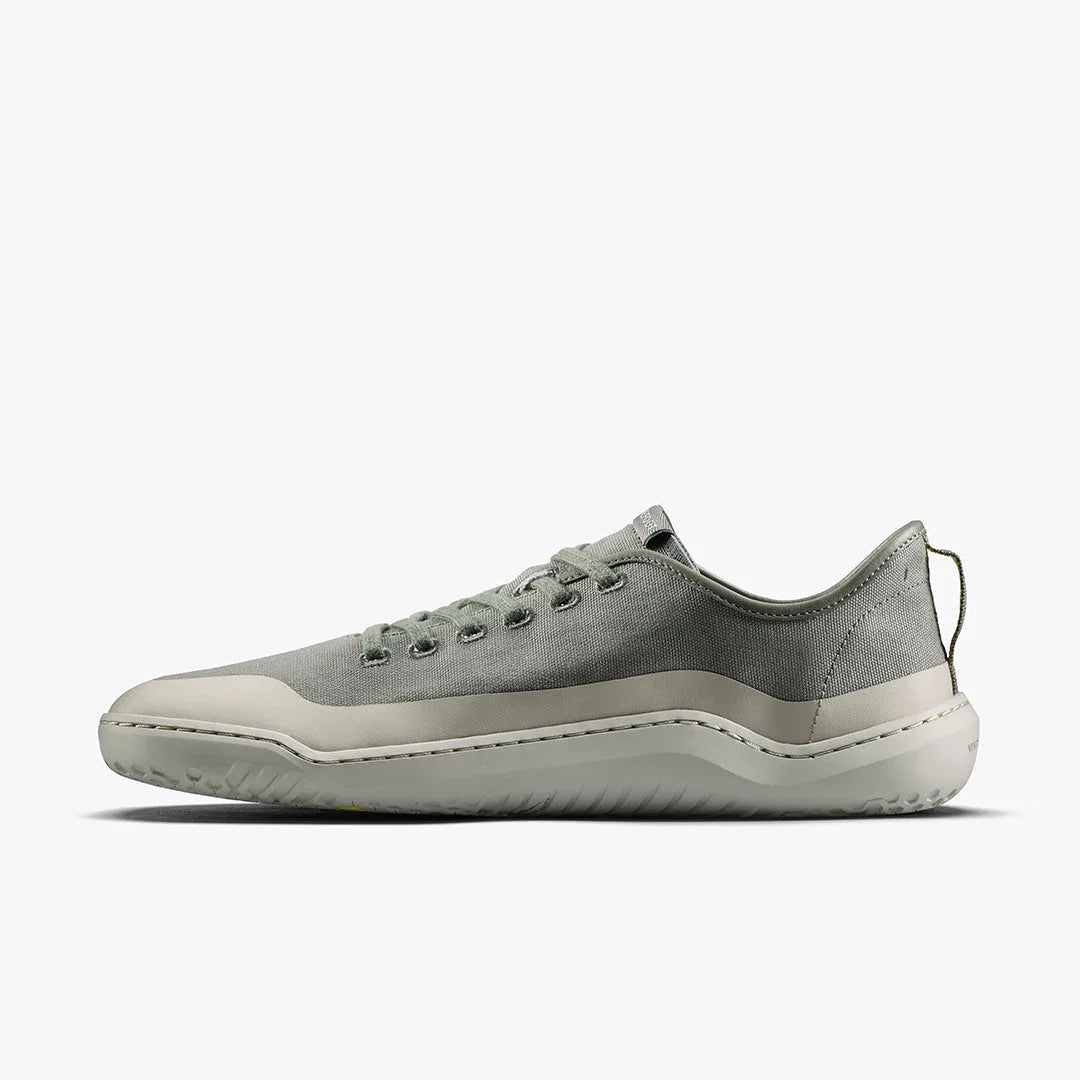 Side view of minimalist light grey low-top sneaker with canvas upper and rubber sole on white background