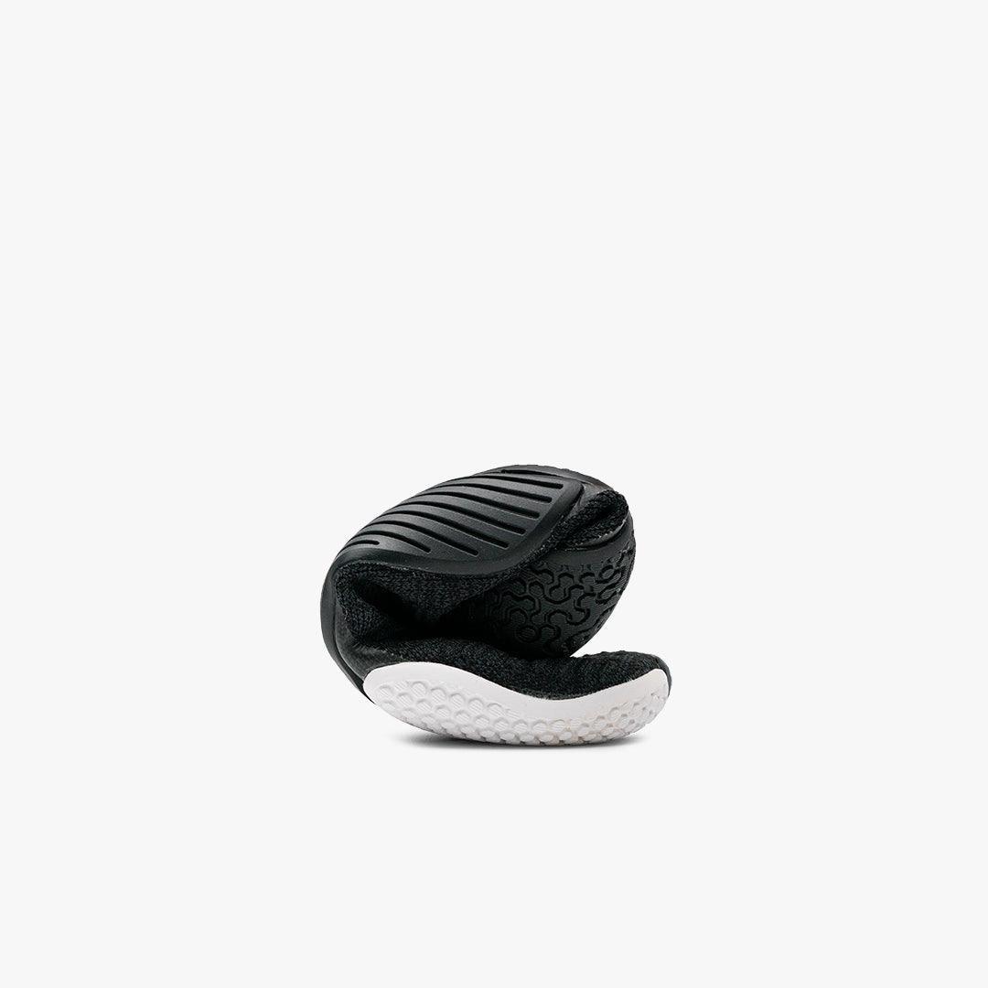 Folded black and white flexible running shoe sole with textured grip on white background