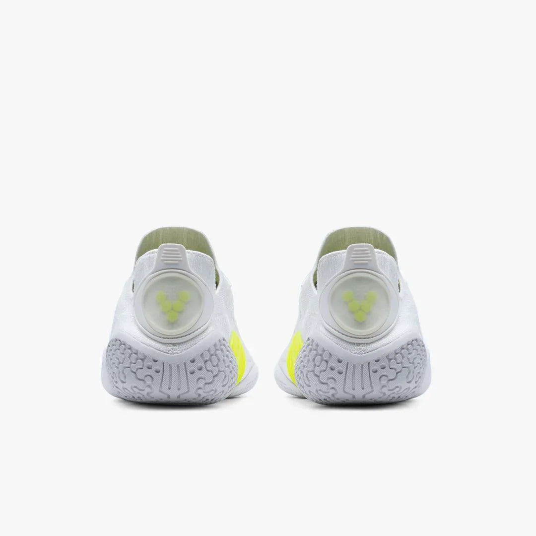 Back view of white and yellow athletic shoes with textured gray soles and circular heel details