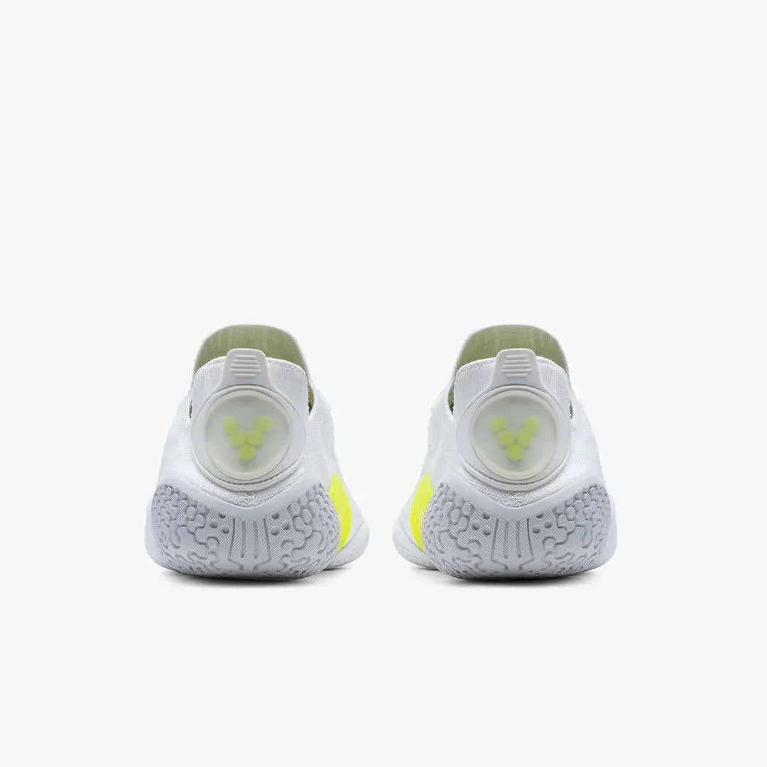 Rear view of white athletic shoes with neon yellow accents and textured gray soles