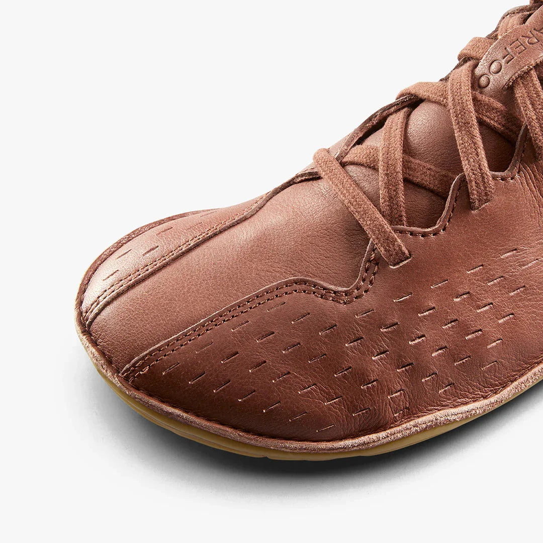 Close-up of brown leather barefoot minimalist shoe with detailed stitching and laces