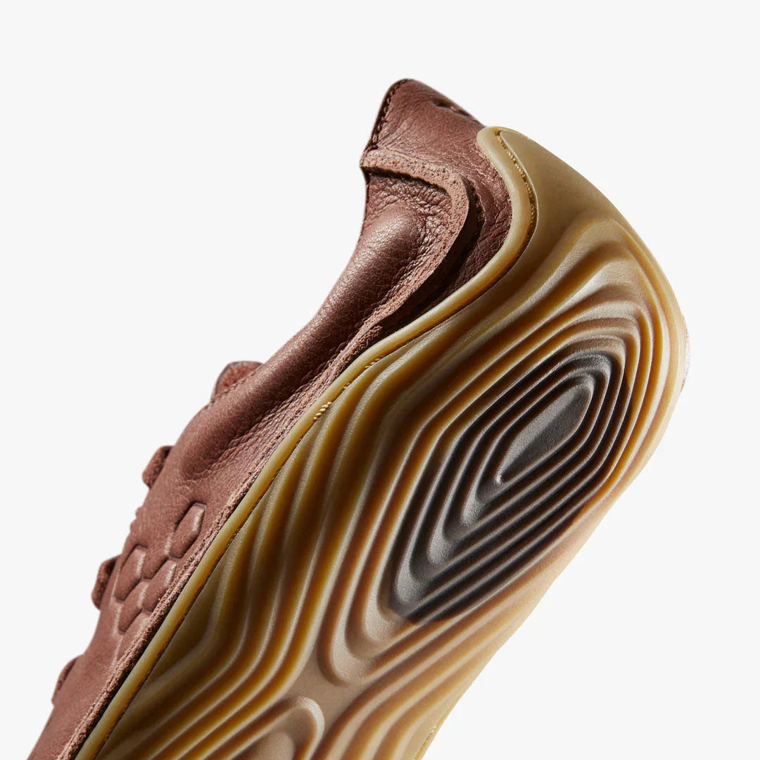 Close-up of brown leather shoe with textured rubber sole featuring wavy patterns