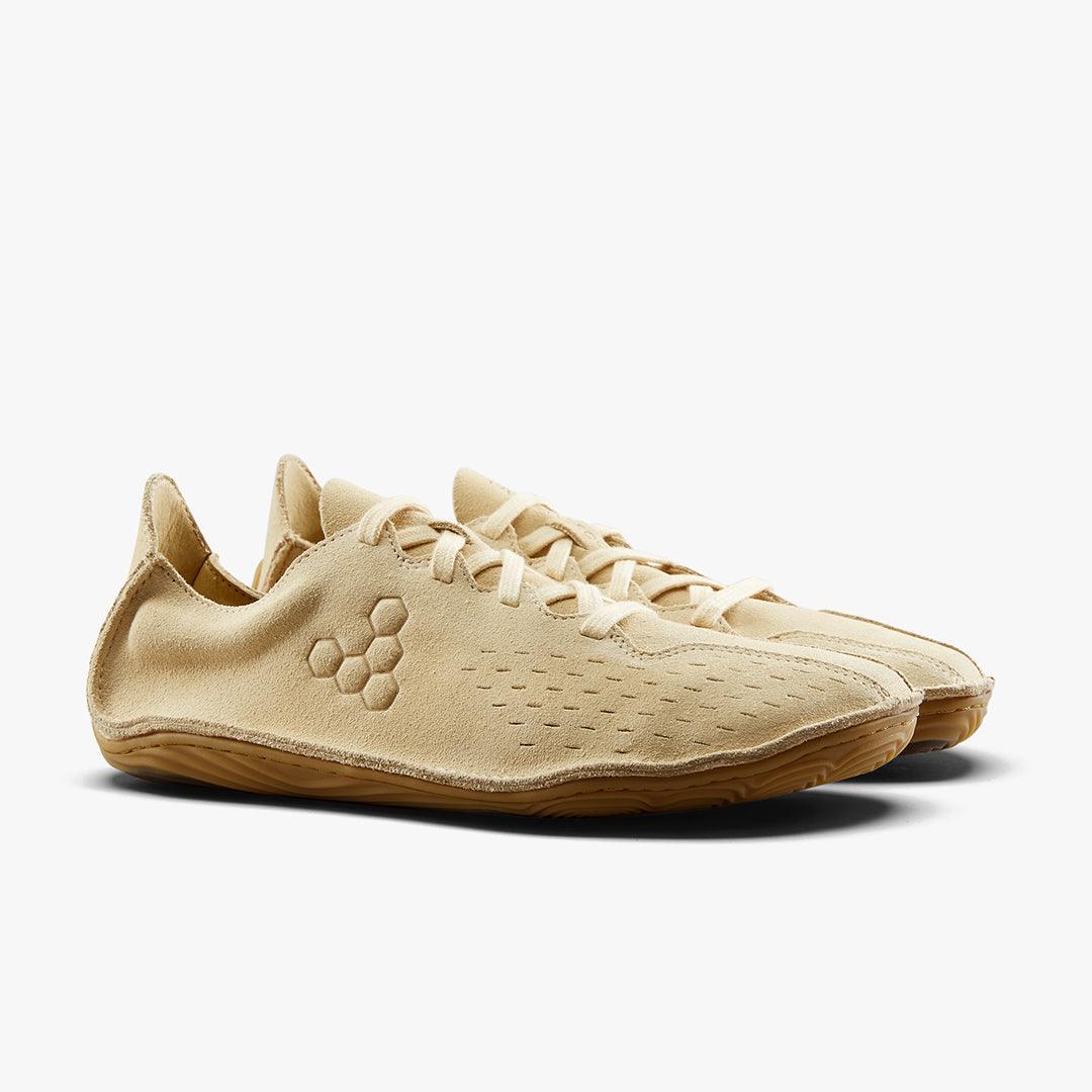 Pair of beige minimalist suede sneakers with honeycomb logo and gum sole on white background