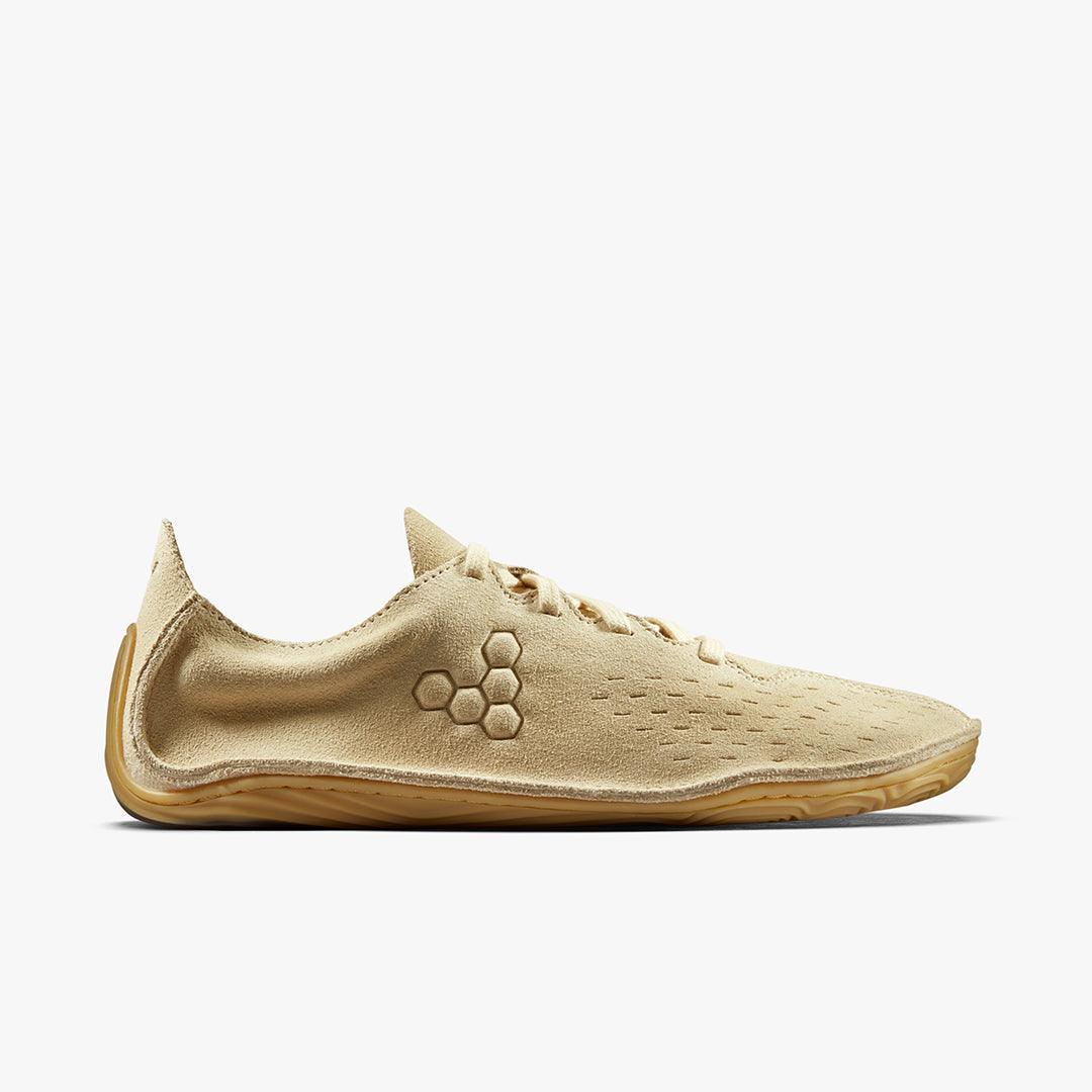 Beige minimalist shoe with suede texture, hexagon logo, side laces, and flexible sole on white background