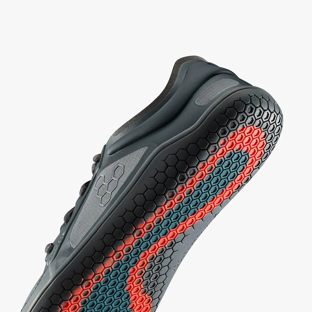 Close-up of black athletic shoe sole with hexagonal tread pattern in red and blue accents