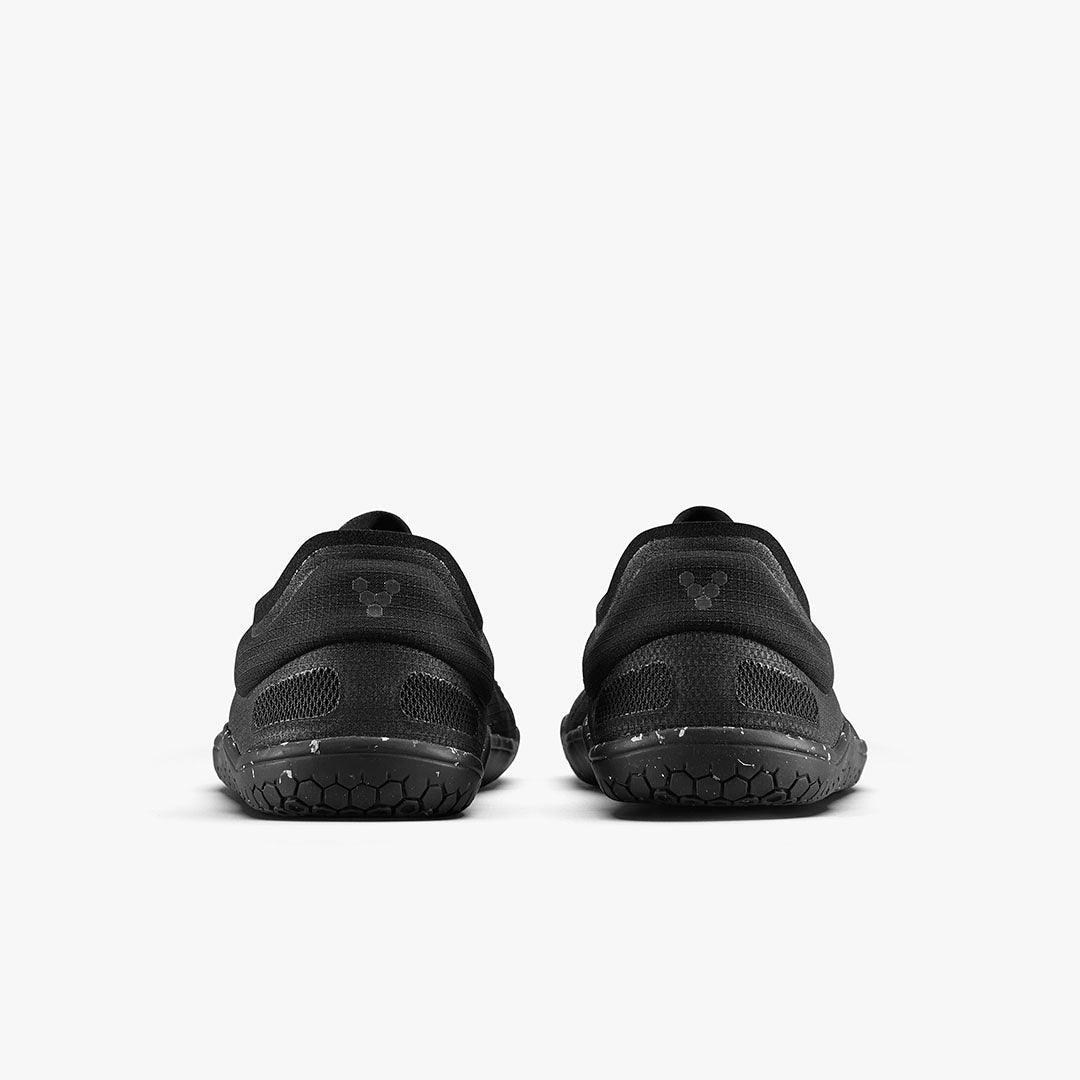 Pair of black minimalist barefoot shoes with hexagonal tread pattern shown from the back