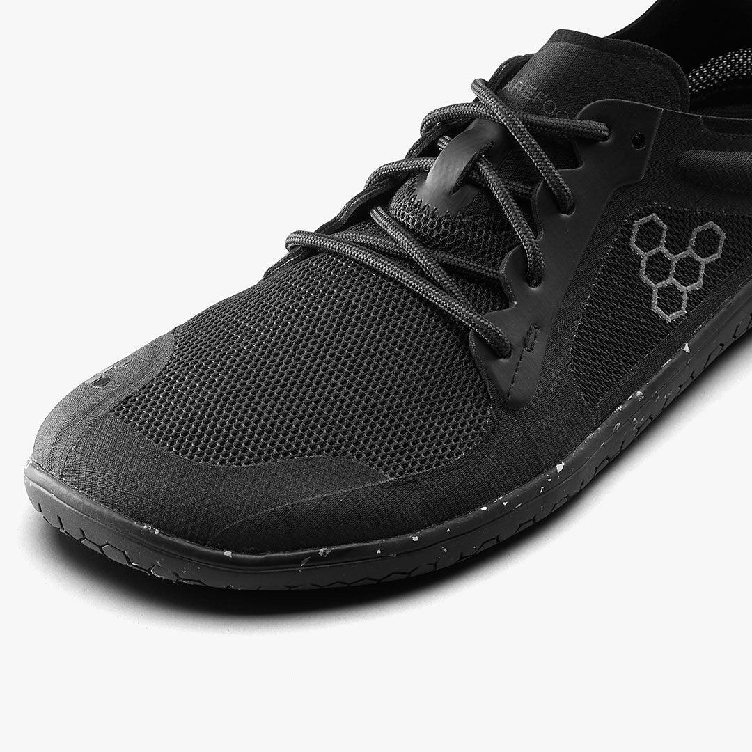 Closeup of black sustainable barefoot shoe with mesh upper and hexagonal logo, The Grounded Sole