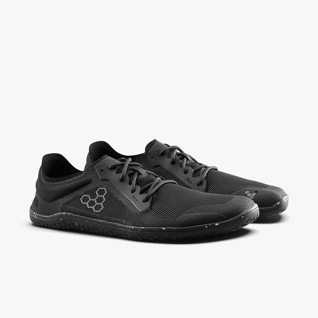 Pair of sleek black minimalist athletic shoes with hex pattern logo on side
