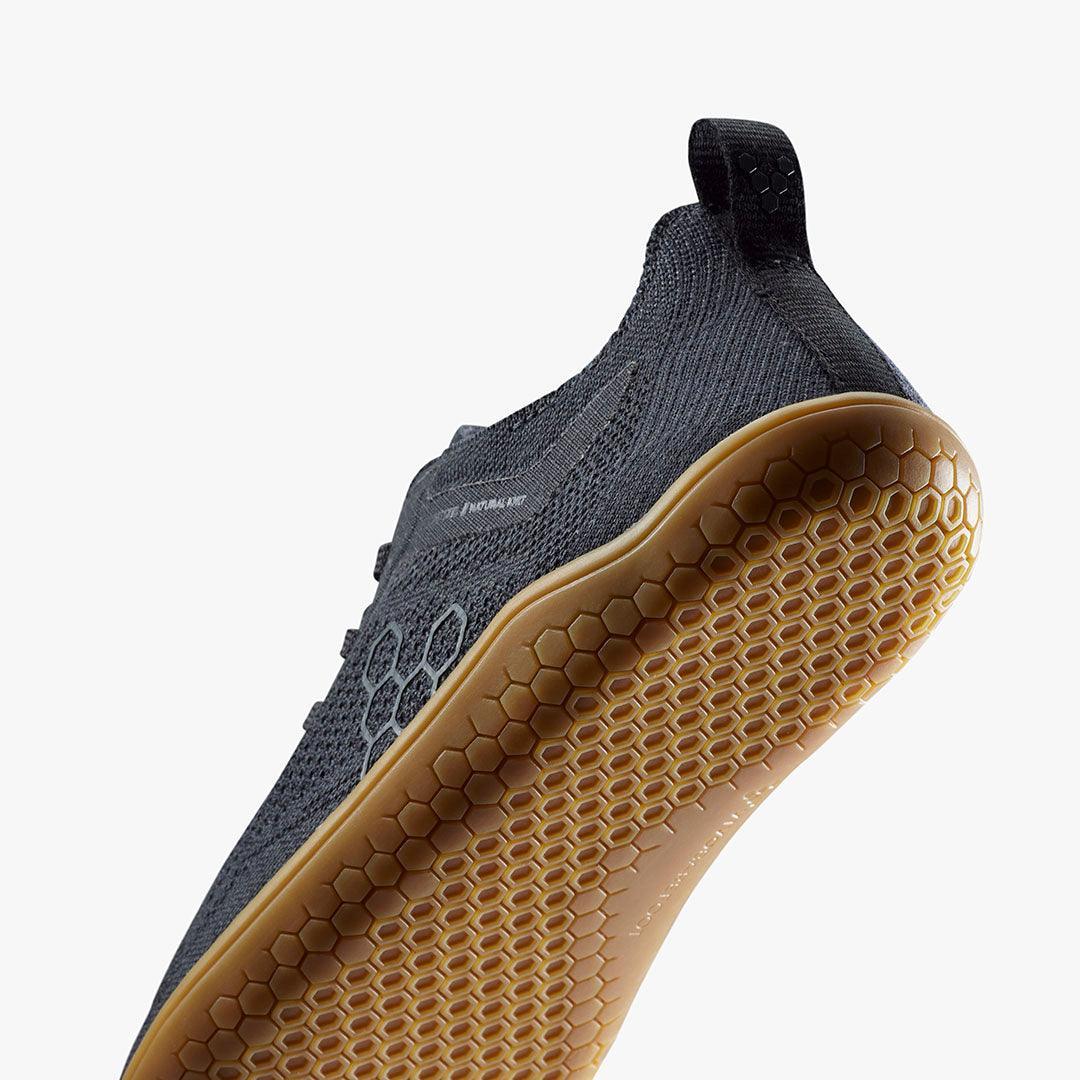Close-up of black athletic shoe with textured honeycomb-patterned gum sole and knit fabric upper