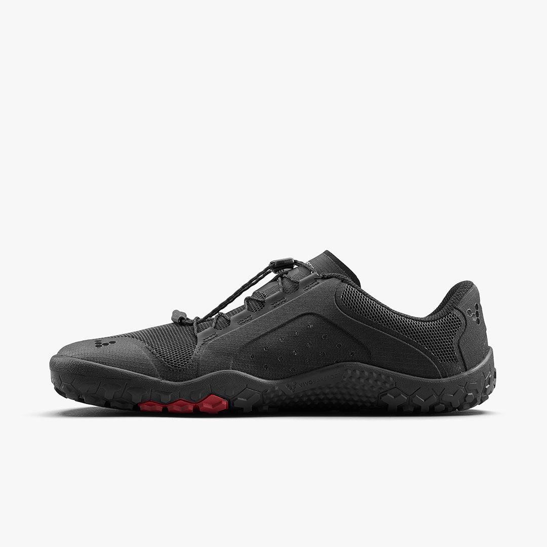 Black barefoot trail shoe with red sole accents, rugged design, from The Grounded Sole