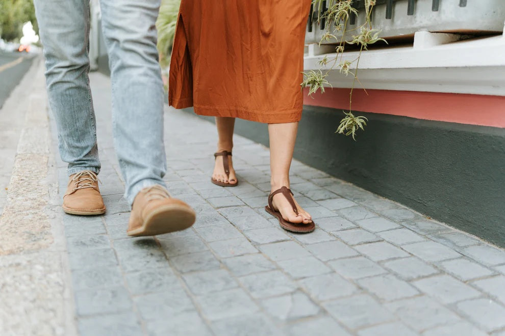 Two people walking on a sidewalk, focusing on their feet and lower legs.